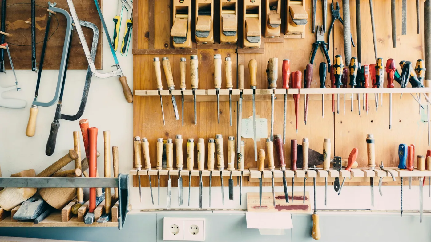 A workshop wall of hand tools in neat rows: saws, chisels, planes, pliers and screwdrivers