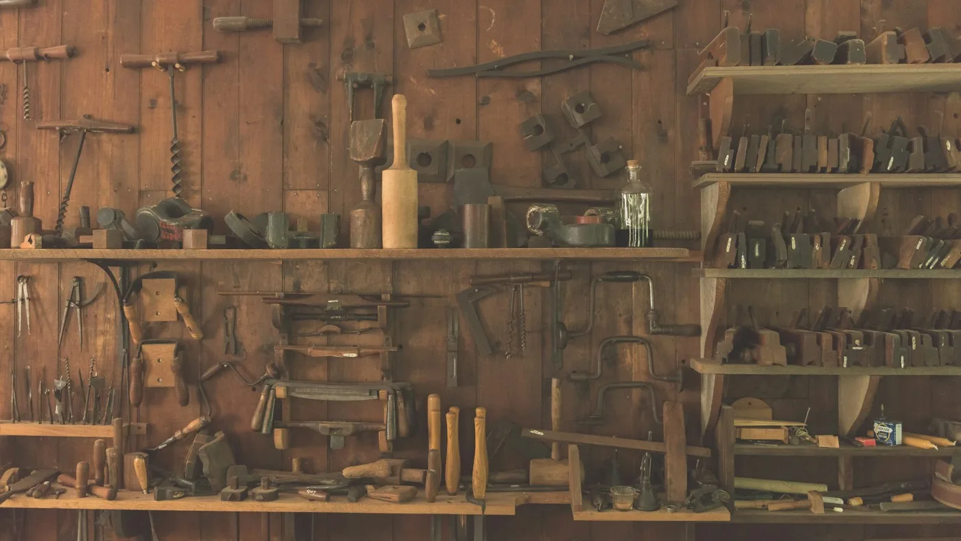 A wall of hand tools arranged on wooden shelves in a workshop