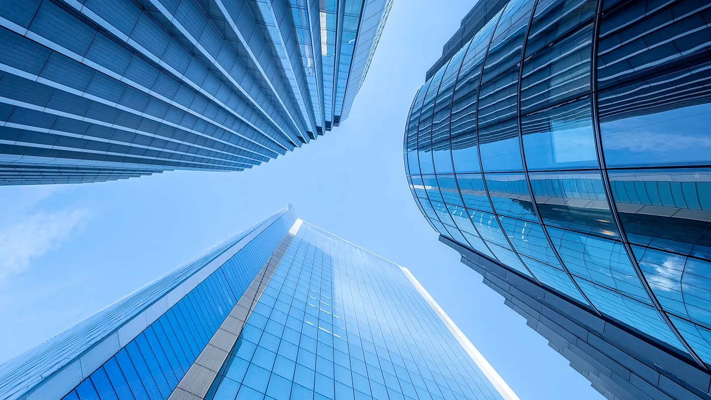 Glass office towers converging above, photographed looking straight up