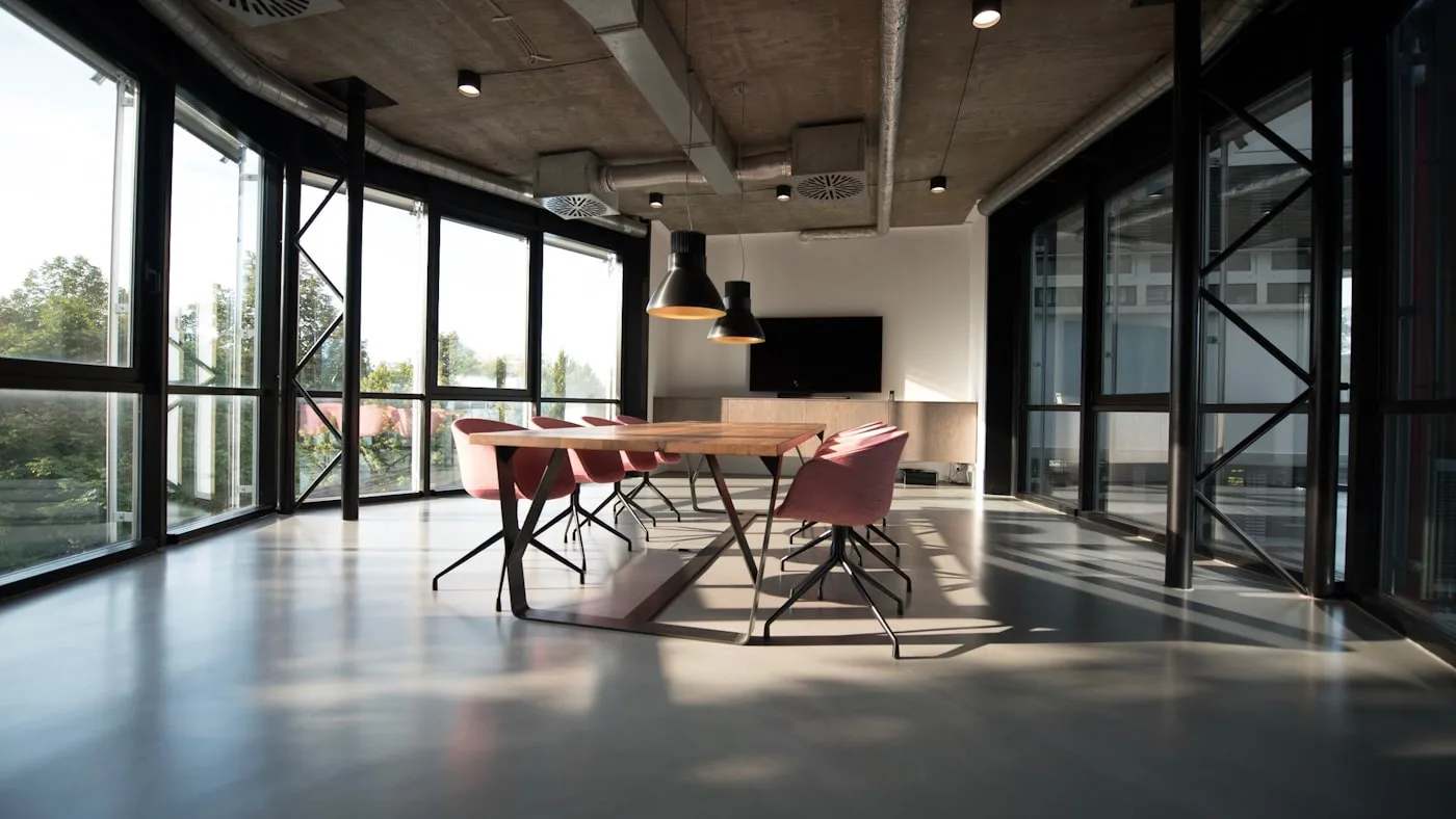 An empty meeting space with a bare table beside floor-to-ceiling glass