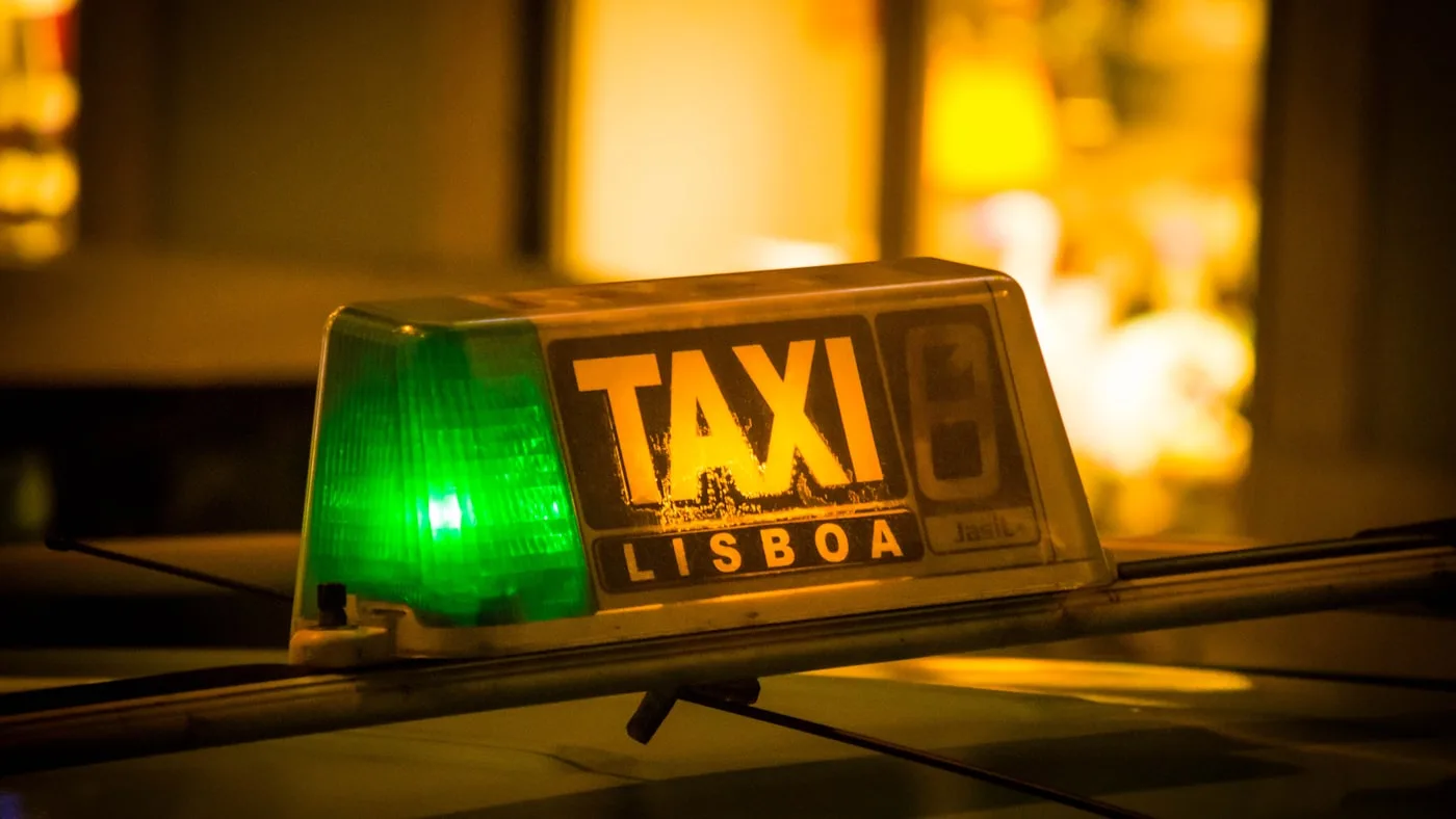 An illuminated green taxi meter sign at night