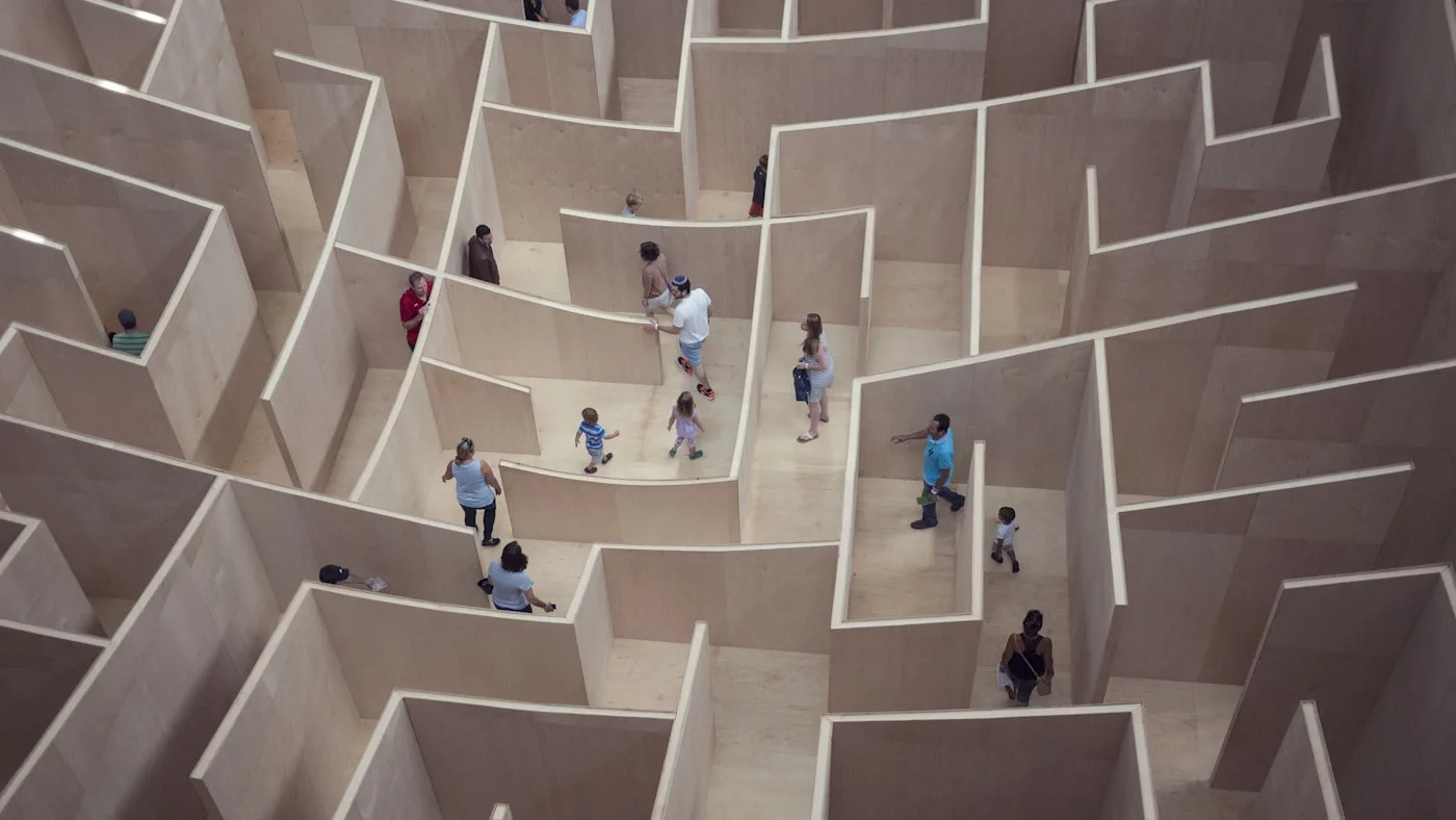 People walking through a large open-air maze seen from above